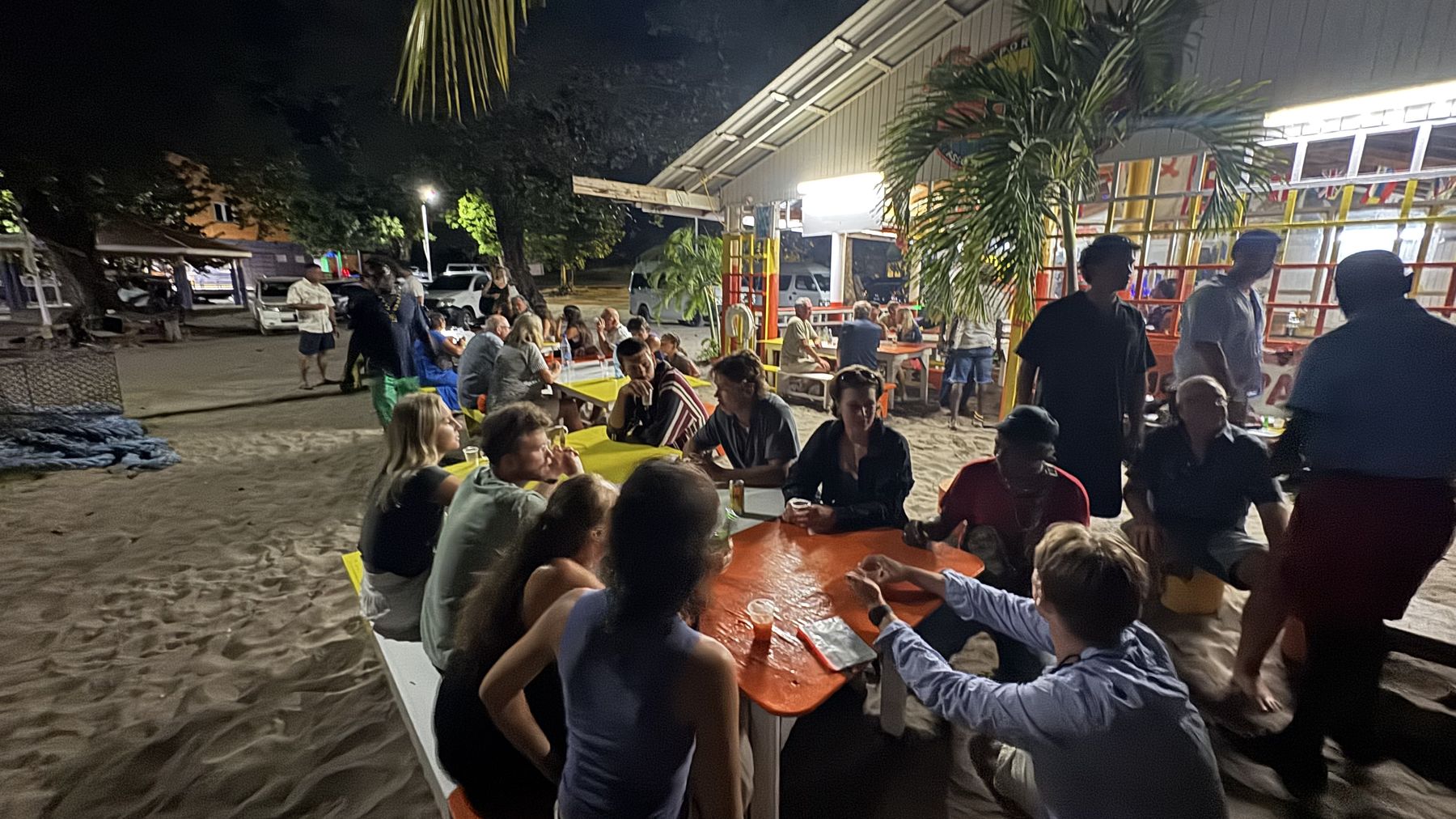 Crew gathered at tables at a beach bar at night