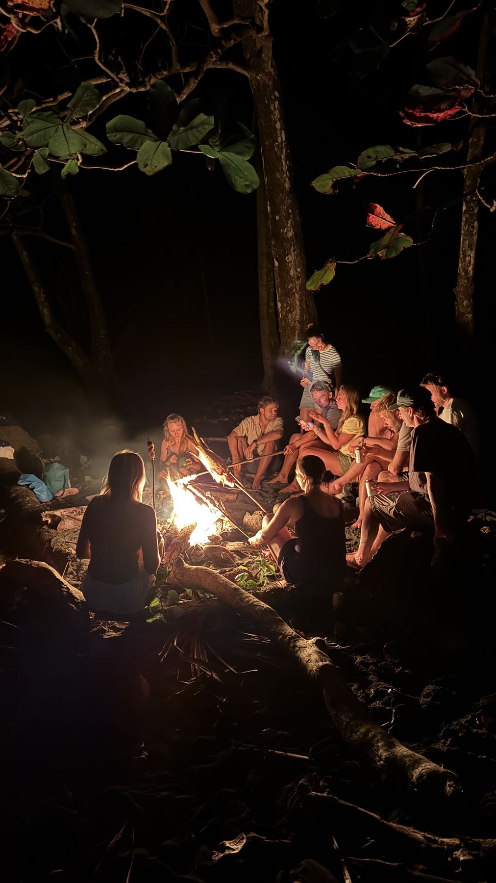 Crew gathered around a bonfire on a dark beach at night