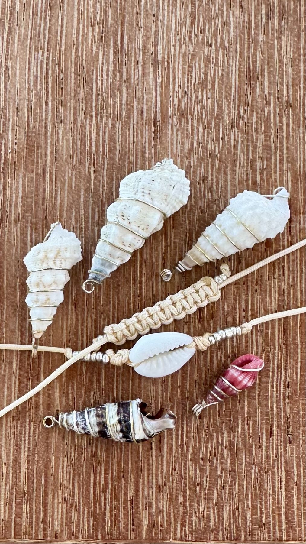 Handmade shell pendants and bracelets laid out on a wooden table
