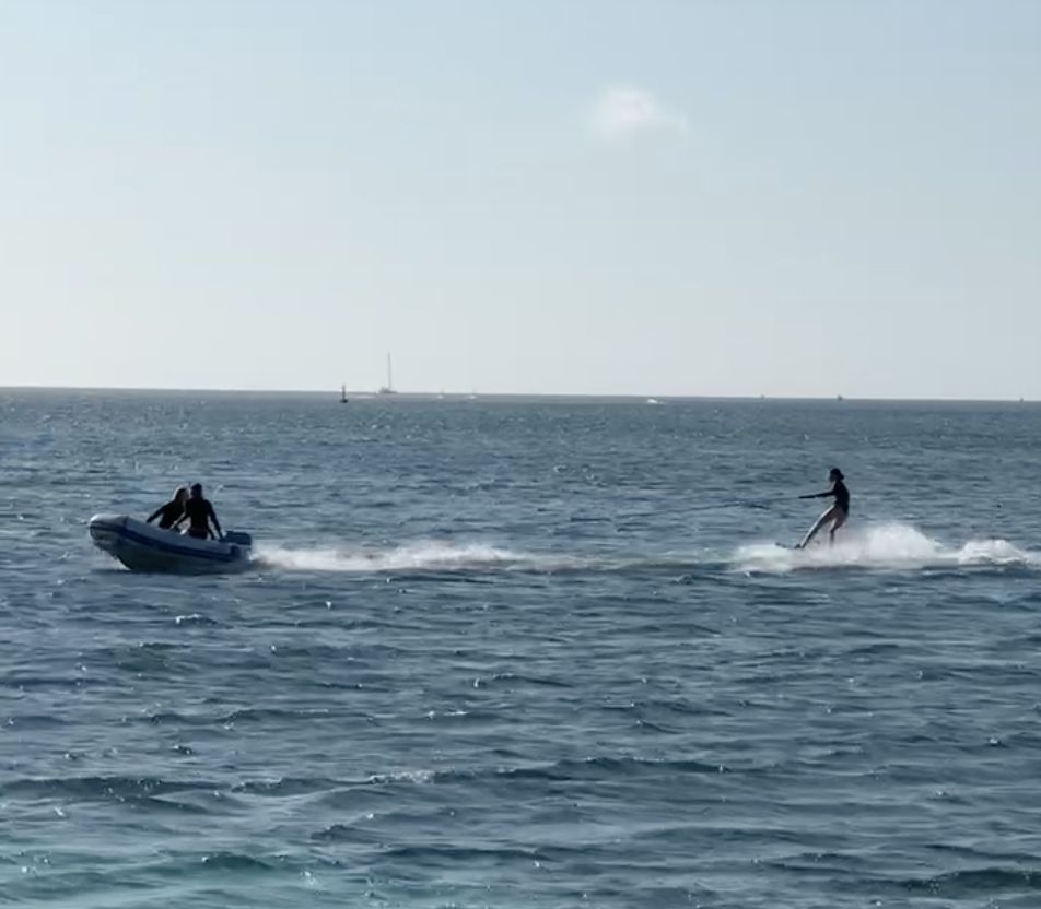 Crew member wakeboarding behind the dinghy
