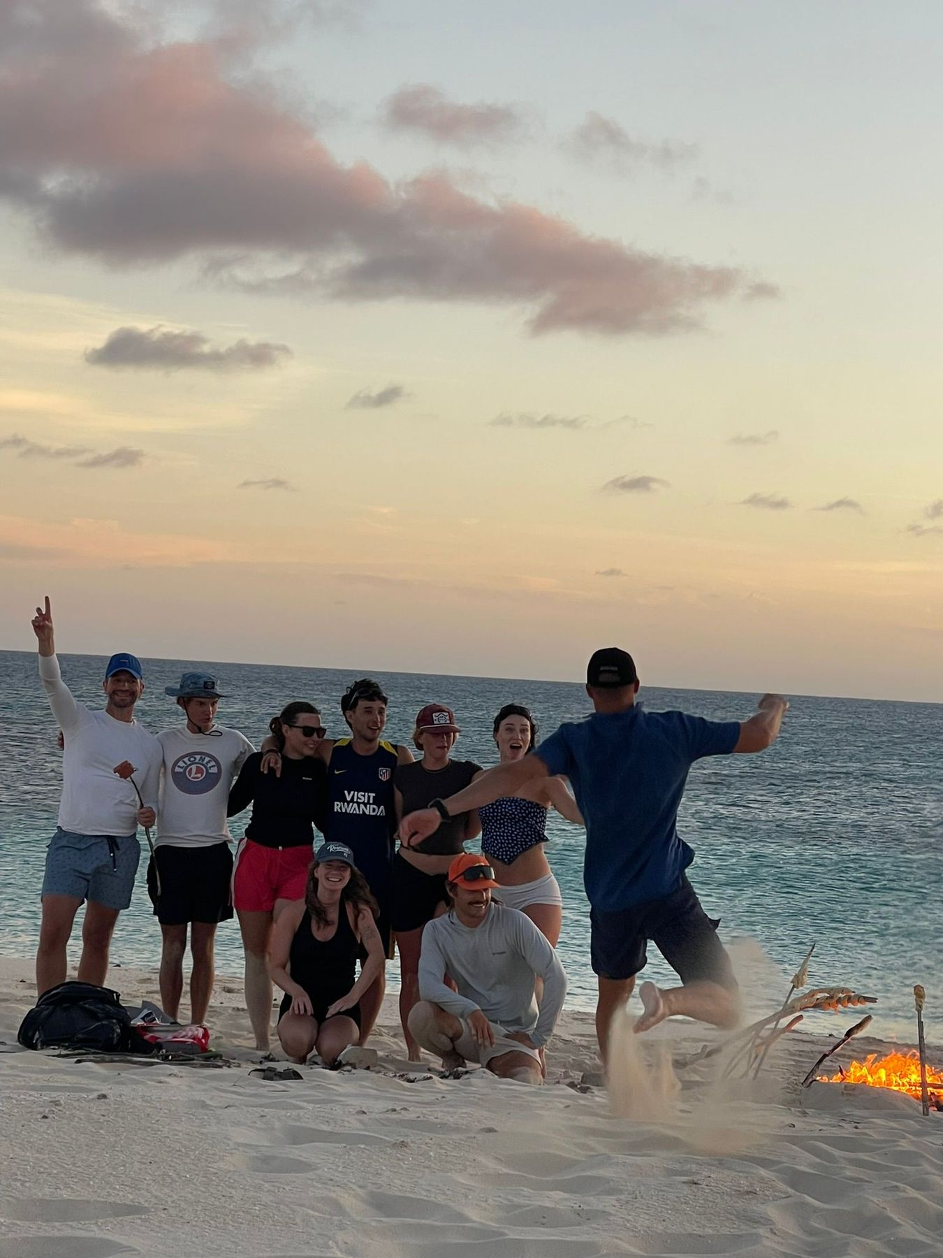 Crew jumping for a photo on the beach at sunset