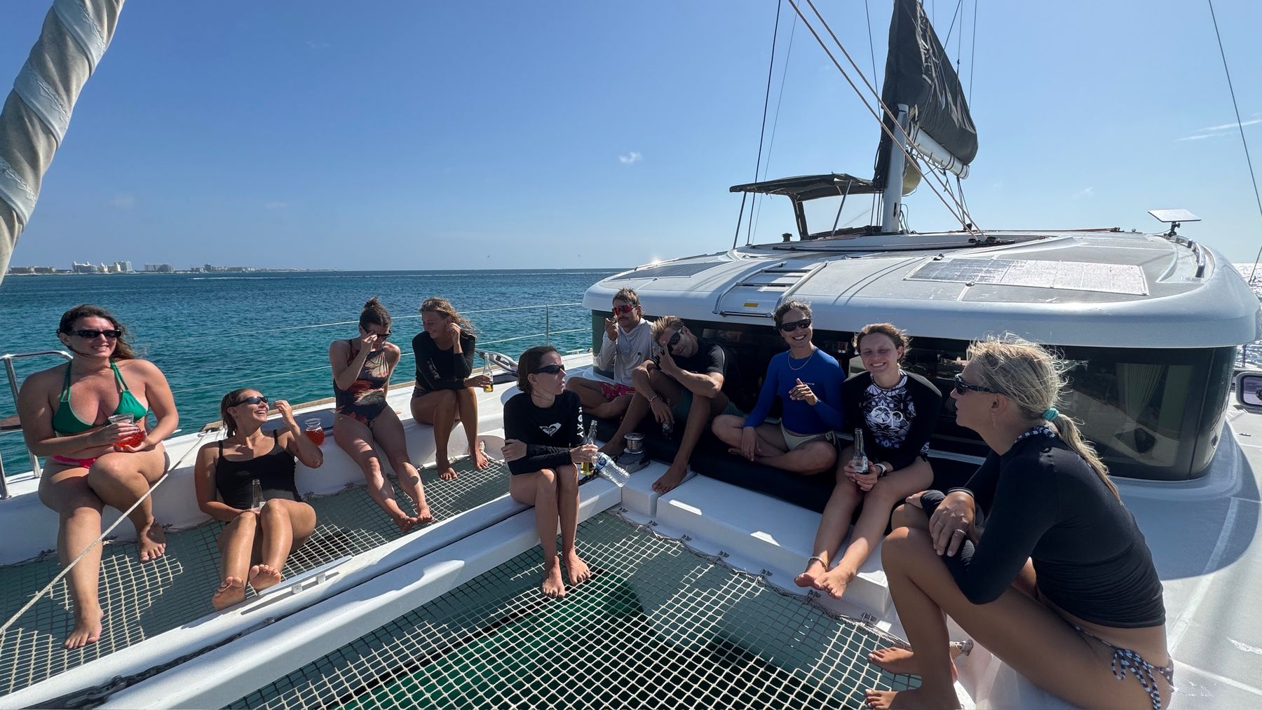 Crew group photo sitting along the deck of the catamaran